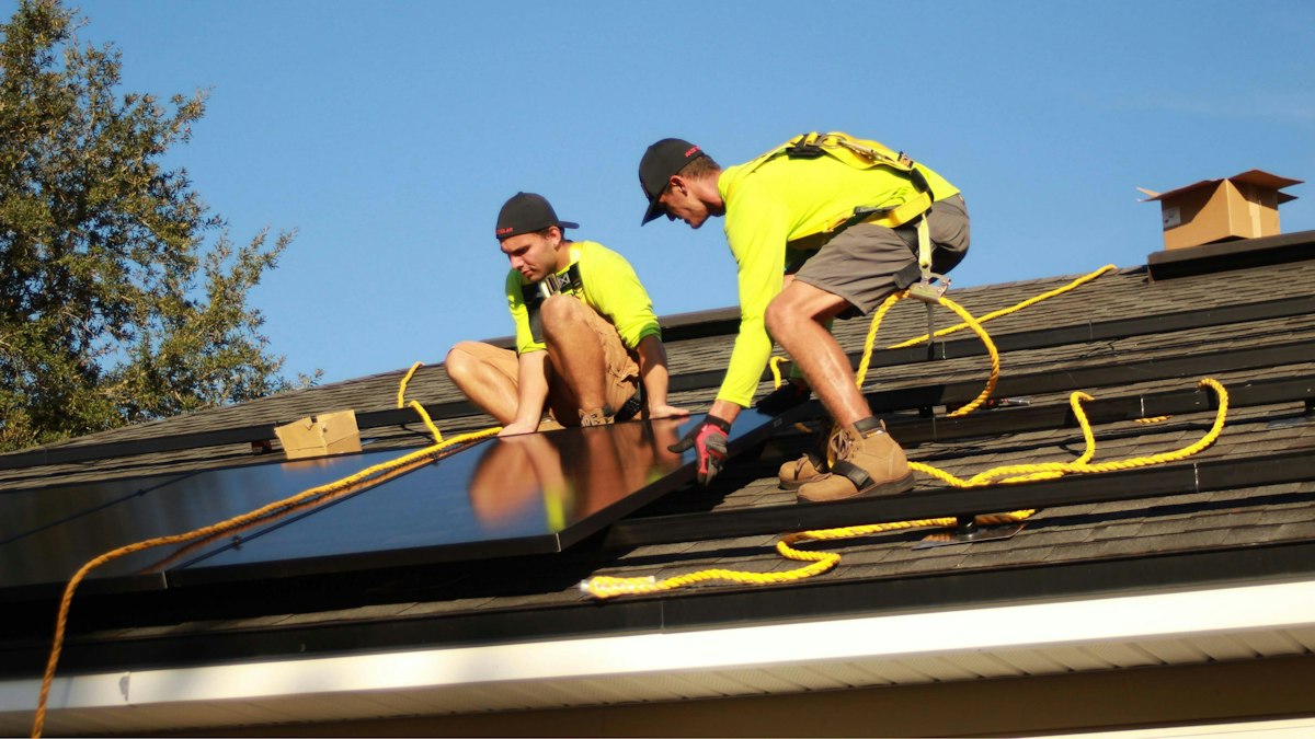 Installers fitting solar panels on a roof